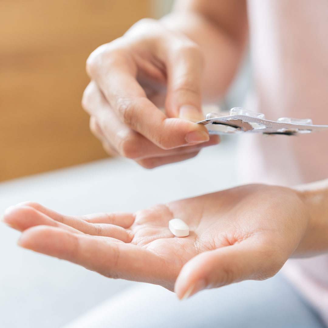 Eine pillenförmige Tablette auf einem Handteller.